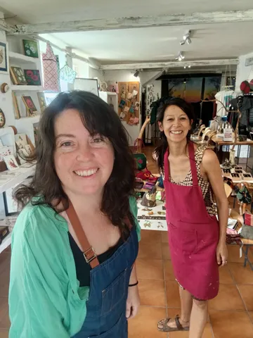 Clara y Marion sonriendo en la tienda, rodeadas de los expositores de artesanía