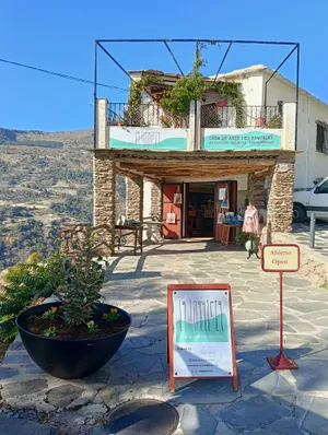 La fachada de La Inquieta con sus carteles, el porche de piedra y el caballete de «abierto» en la calle