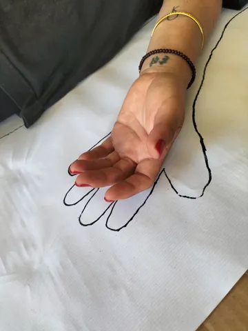 Una mano sobre su silueta dibujada en papel durante una sesión de arteterapia