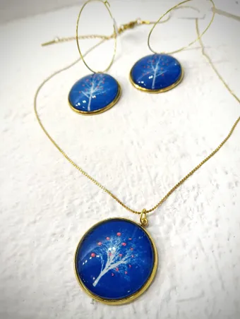 Collar y pendientes dorados con cianotipias en miniatura de un árbol sobre fondo azul