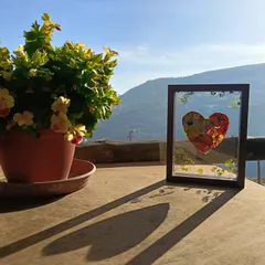 Un corazón de flores prensadas enmarcado a contraluz, con las montañas de la Alpujarra detrás