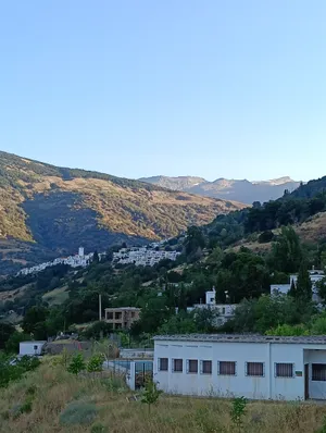 El valle del Poqueira con Capileira encaramada en la ladera y las cumbres de Sierra Nevada al fondo